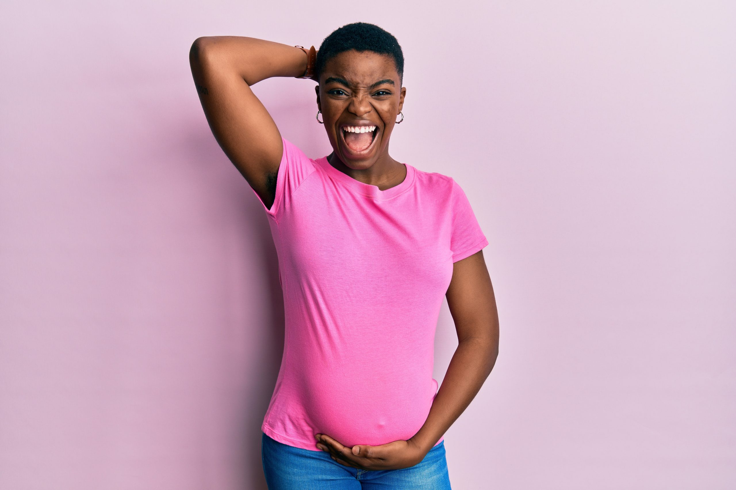 Young African American Woman Expecting A Baby, Touching Pregnant Belly Crazy And Scared With Hands On Head, Happy With Open Mouth